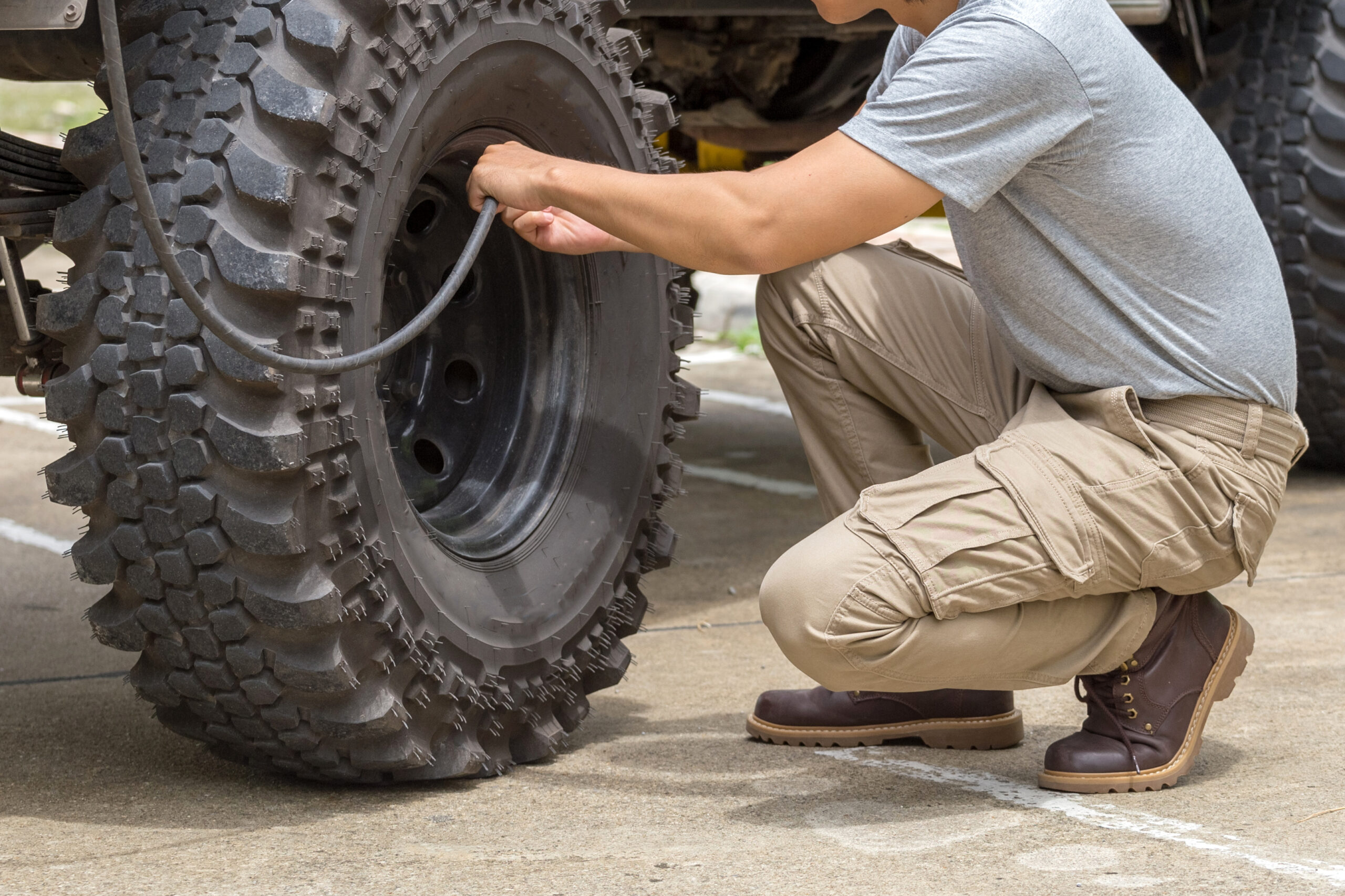 man pumps a offroad car wheel with a compressor.